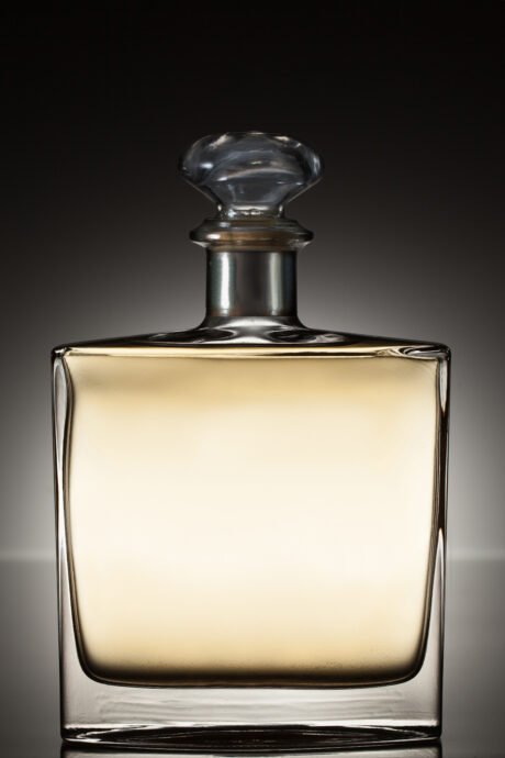 Liquor in a square bottle on a grey gradient background. side view.